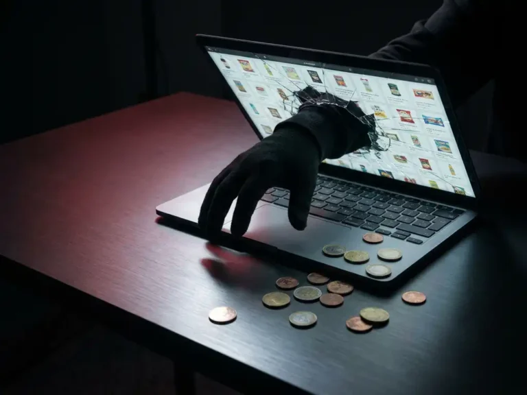Behandschuhte Hand greift durch rissigen Laptop-Bildschirm auf Google-Shopping-Raster, Euromünzen auf modernem Schreibtisch verstreut.